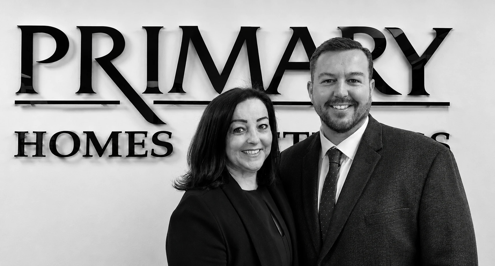 Primary Homes logo with Dawn and Dean (Business Partners) standing in front